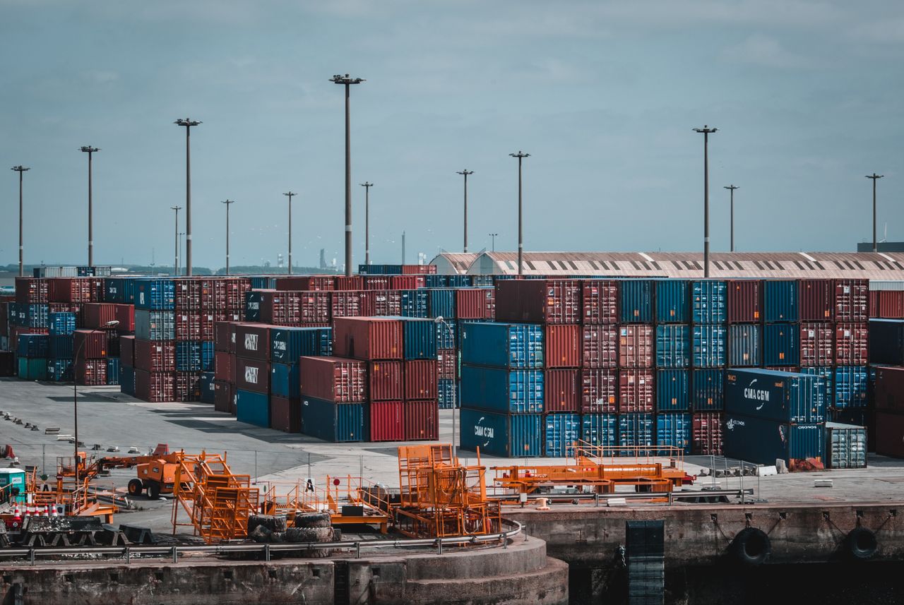 gallery-01 Colorful cargo containers stacked at a busy industrial port, showcasing global trade.