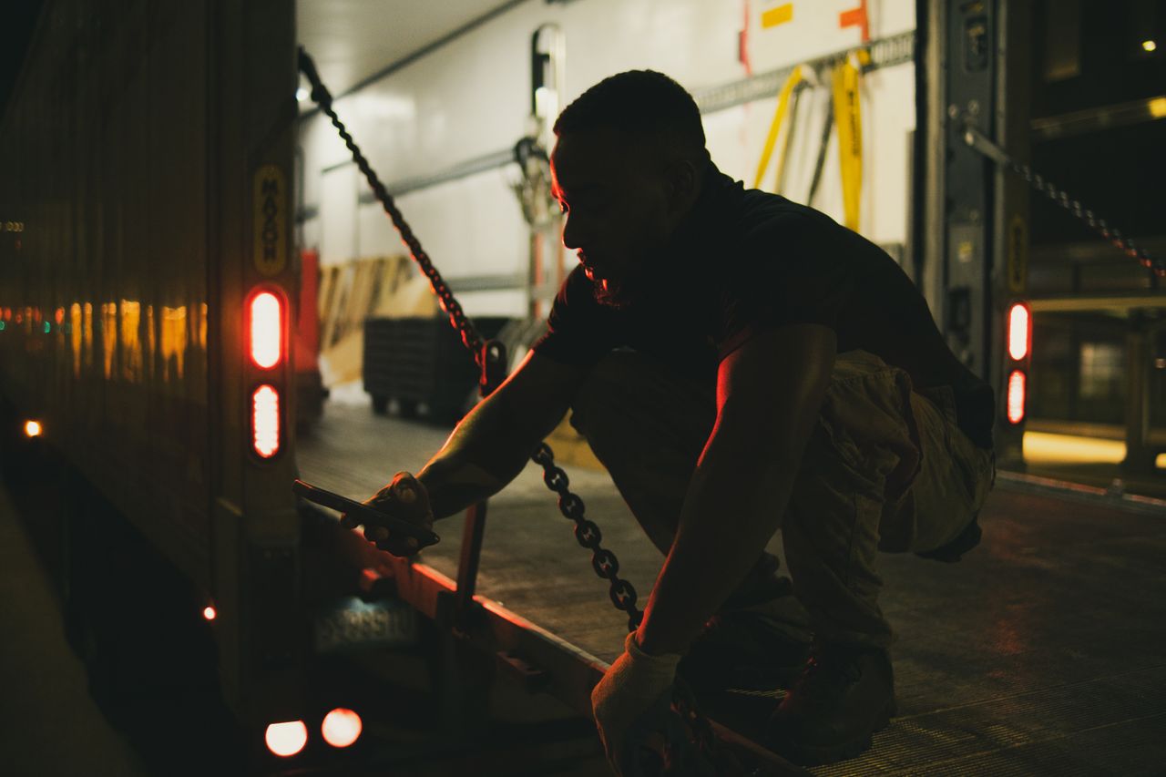 services-03 Man securing chains on a cargo truck at night in Houston, Texas.