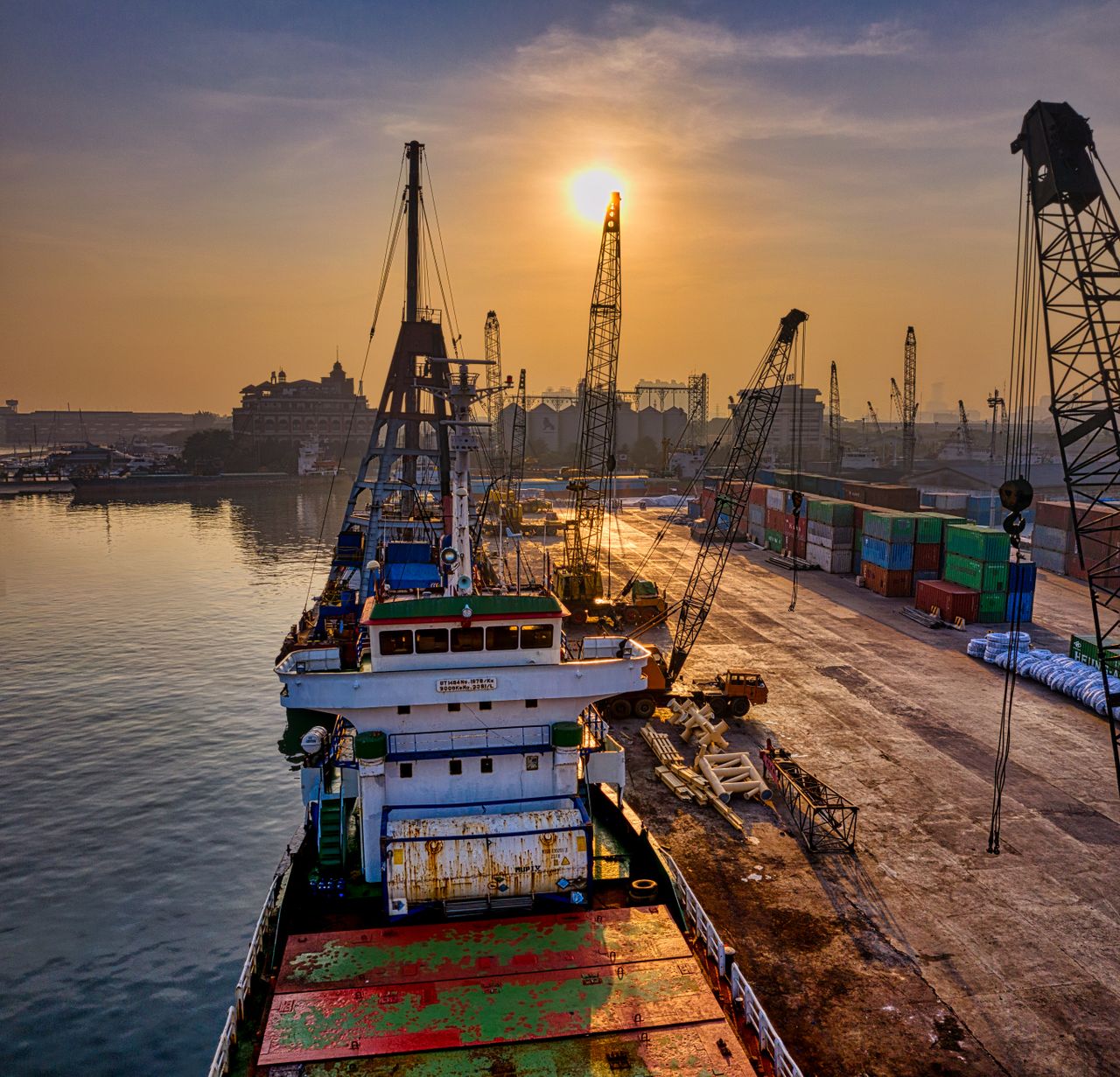 services-02 A vibrant scene of cargo operations during sunrise at a busy port in Indonesia.