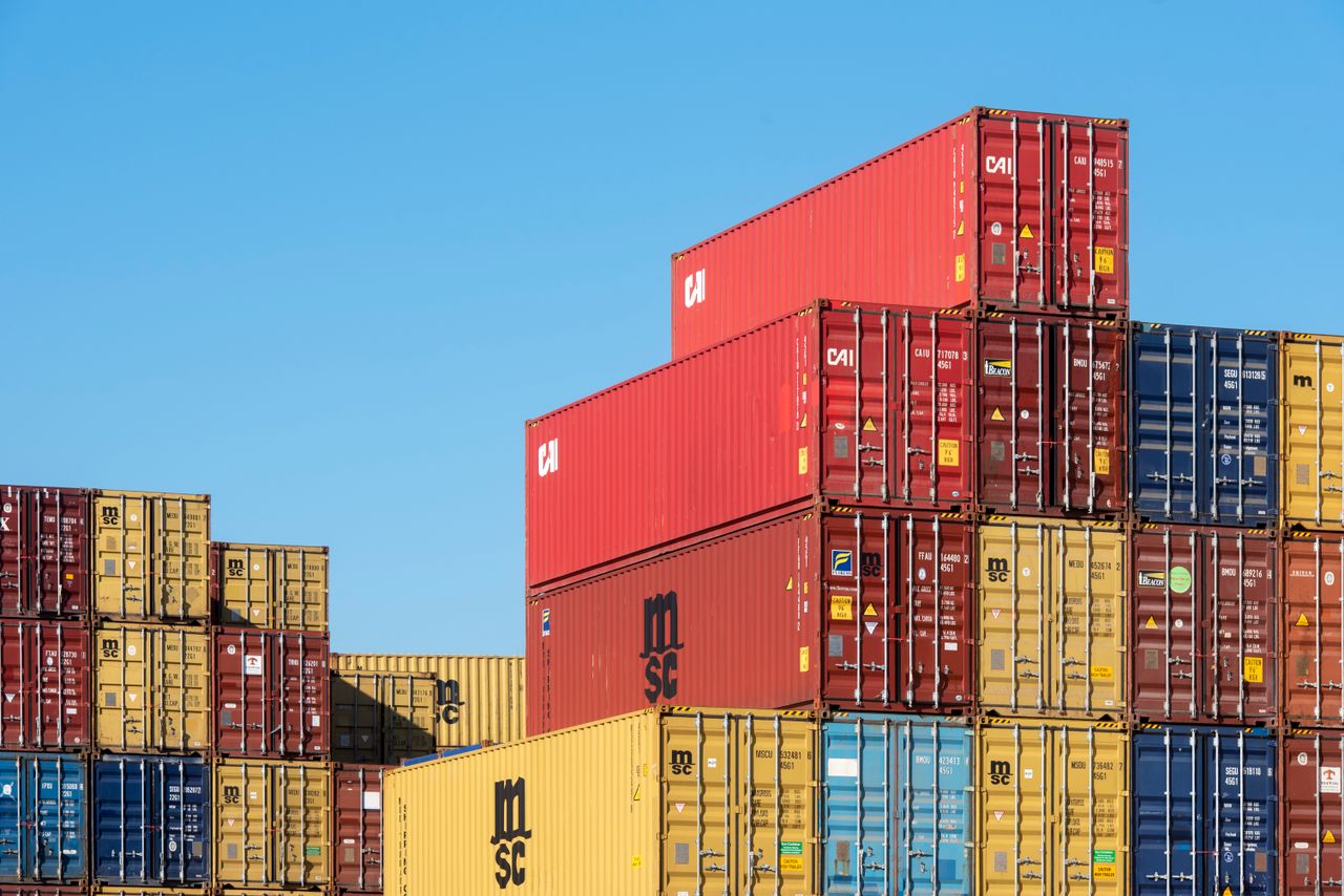 gallery-02 A vibrant collection of stacked shipping containers under a clear, blue sky. Ideal for logistic themes.